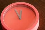 Modern circular red clock face or dial in minimalistic style with only hour and minute hands, oblique angle view
