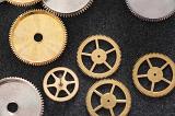 Golden and silver cogwheels, parts of a vintage mechanical clock, close-up on dark gray