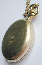 Gold vintage full hunter pocket watch with a tooled engraved case and chain displayed closed at an angle