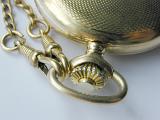 Close up of the silver winder and chain on a vintage pocketwatch with an embossed textured case