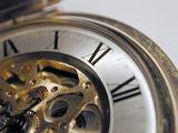 close up on the dial of a brass pocket watch with roman numerals