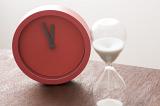 Red modern clock and egg timer or hourglass with running sand measuring the passing time