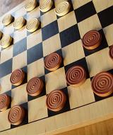 traditional game of strategy: counters on a wooden draughts board