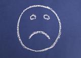 an unhappy face with a frown drawn with chalk on a purple blue background