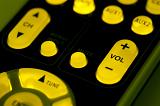 Backlit remote control keypad with glowing yellow buttons with focus to the Volume