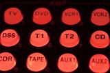 Red illuminated control buttons on an entertainment and audio centre showing the functions in text in a close up view