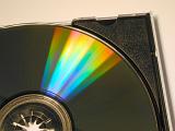 Iridescent display of light on a DVD or CD disc in a colorful spectrum as it lies in its plastic box