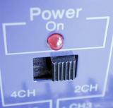 Power slider with a red light below on blue electronic equipment in a close up view with focus to the switch
