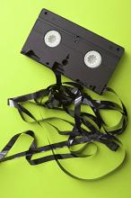Tangled destroyed video tape that has unwound from the cassette on a lime green background in a communication and entertainment concept