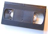 Unlabelled generic VHS video cassette tape in a black plastic case on white viewed from above