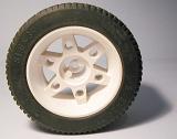 toy car tyre with a white rim and hub and new tread standing upright on a grey background with shadow