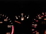 Illuminated gauges on a car dash board display centered on the fuel readout with the needle in the off position