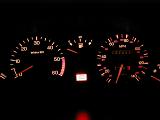 Close up on automobile dashboard lights with tachometer and speedometer. Fuel guage at empty with battery light on.