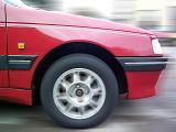 Front side panel and tyre of a moving red car driving on a street in a close up view of the bodywork