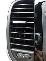 Car side air vent on the dashboard in a white car viewed along the door and handle with control knob and slider