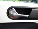 Recessed silver metal car door handle on a white car in a close up view