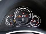 Cluster of car instruments on a dashboard with a speedometer, warning light and fuel gauge on round dials on black trim