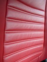 Red leather texture in a vehicle interior showing the ridges seat support at an oblique angle in a modern luxury car