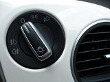 Car light switch on a dashboard of a white car with controls for full beam and parking lights