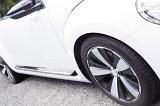 Angled close up on side of white sports automobile with complementary black and chrome hubcaps