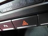 Red triangular hazard warning light switch on a car dashboard for use in an emergency in a close up view with the passenger airbag above