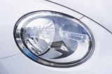 Modern oval car headlamp on a white car in a close up view