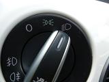 Headlight switch on a white car dashboard positioned to full beam in a travel and transport concept