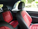 Red and black seats in a modern car parked outdoors in a garden showing both the front and rear upholstery
