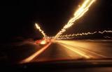 View from inside moving car of wavy streetlights and headlights from other vehicles with copy space