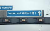 Road signs for London and Watford on the M1 motorway with directional arrow on an overhead girder