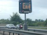 Blurry image taken on expressway of sign that reads end as motorcycle speeds by
