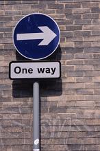 One Way street or traffic sign and uni directional arrow pointing to the right against an urban brick wall with copy space