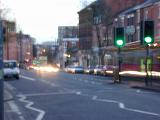 Blurry daytime street scene with moving vehicles and trailing light streaks from headlights