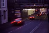 Motion blurred urban traffic driving at night under a bridge or overpass in a commercial street