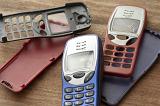 Collection of colorful mobile phone covers from retro push button devices lying on a wooden table, one with a smashed screen