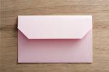 Pink envelope with an open flap lying face down on wood in a communications or correspondence concept