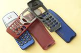 Assorted red, blue and black retro mobile phone cases or covers for push button telephones with one having a cracked screen