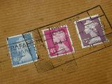 Cancelled British postal stamps on a brown paper parcel showing the fee for dispatching the package through the mail