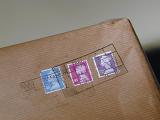 Cancelled British stamps for payment of postage on a brown paper parcel sent by Royal Mail