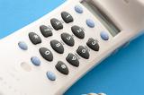 Keypad or dial pad on a white plastic terrestrial telephone handset viewed close up over a blue background in a communications concept