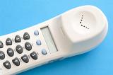 Close up of a land line phone keypad on a white handset receiver lying on a blue background in a communications concept