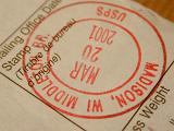 Postal date stamp in red ink for the US postal services on a dispatch notice for a parcel or package