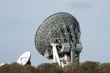 Large parabolic ground station satellite telecommunication dishes on a hilltop on the skyline viewed from the rear