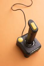 Retro wired computer gaming joystick with yellow buttons for playing video games viewed from above in an entertainment concept