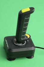 Computer joystick with cable standing against green background