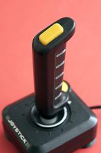 Retro gaming joystick or controller for playing video games with handle and buttons on a red background viewed high angle in an entertainment concept