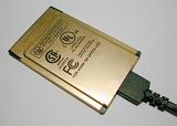 Close up on brass colored internal PC modem with plug over neutral gray background