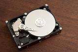 Open 3.5 inch hard disk drive HDD with head over disks surface, close-up from above on dark wooden table