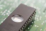 Eprom memory chip with round window on the back installed on electronic circuit board, close-up view from high angle