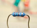 Close up of a blue electronic resistor, isolated on a blurred background.